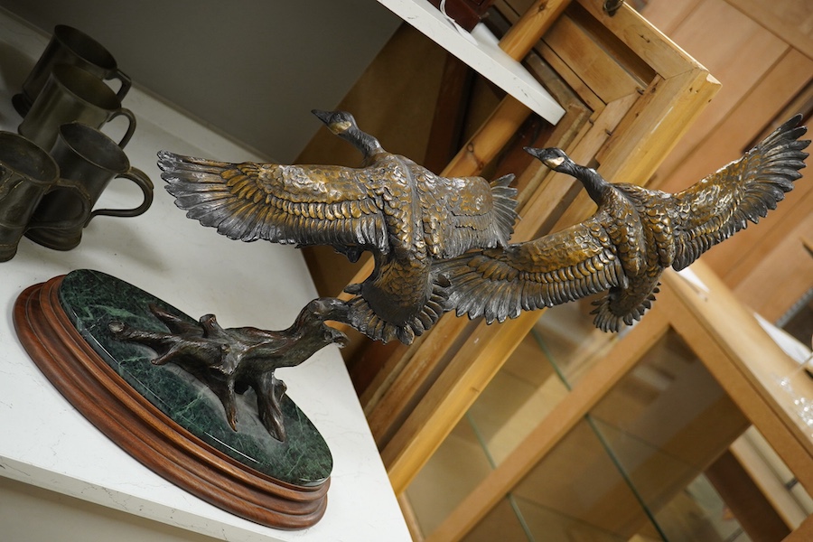 A modern large cast bronze sculpture of two flying geese, on an oval plinth, 90cm wide. Condition - good